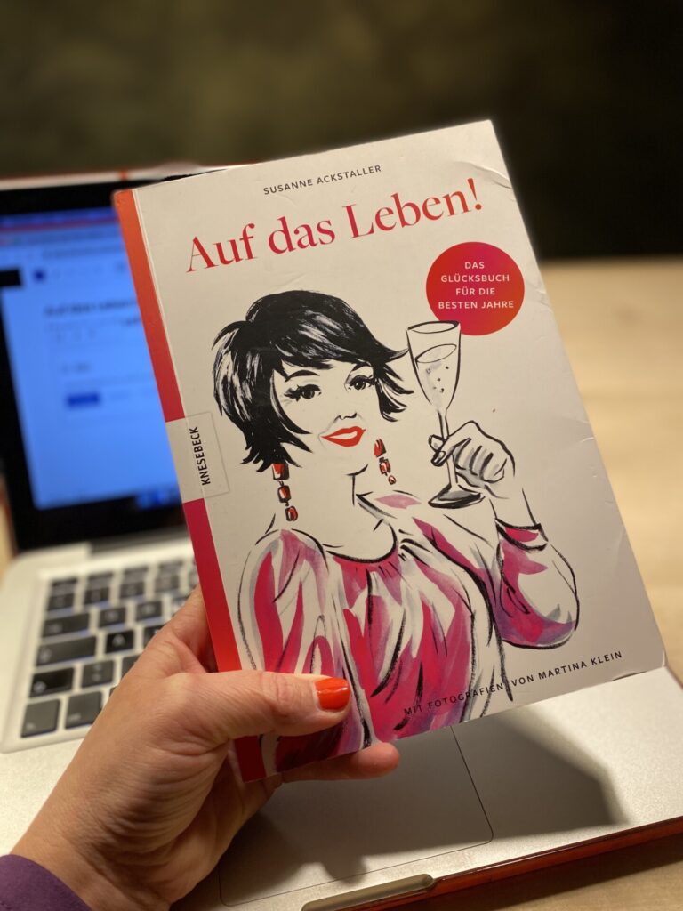 Eine Hand hält das Buch "Auf das Leben" von Susanne Ackstaller in der Hand